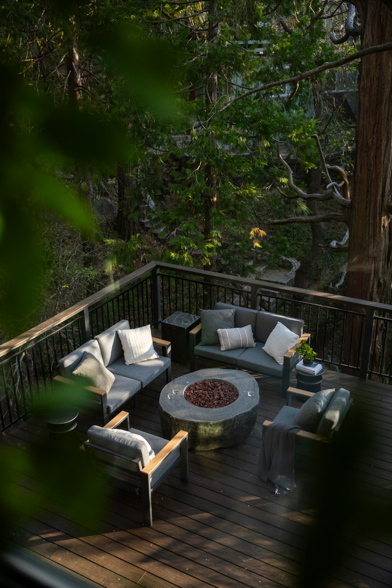 Deck lounge and fire table seen from above through the leaves