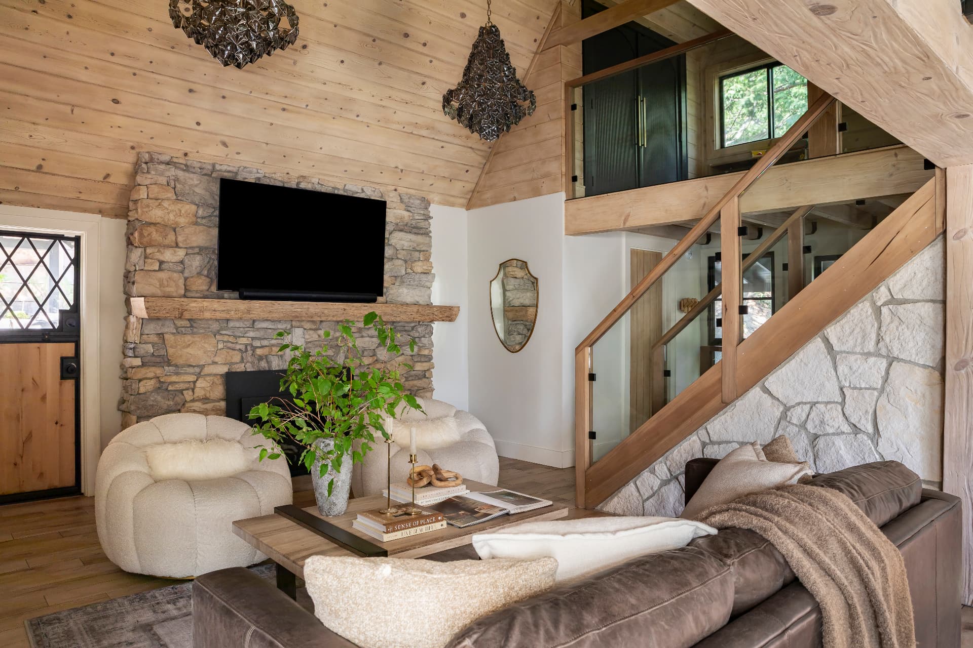 Vaulted living room with stone fireplace, sculptural chandeliers and open stair