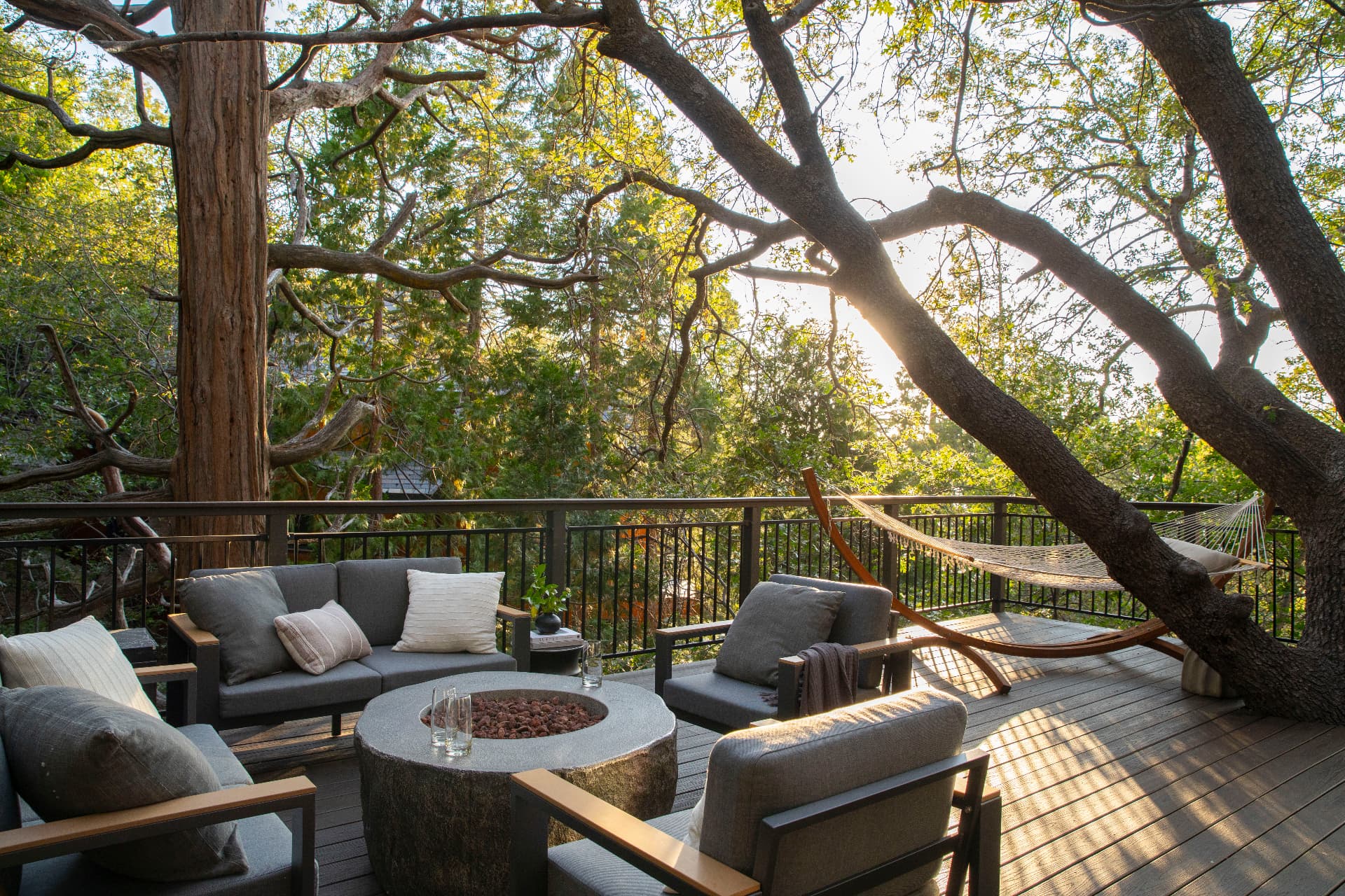 The main deck built around a mature oak, with lounge seating, fire table and hammock