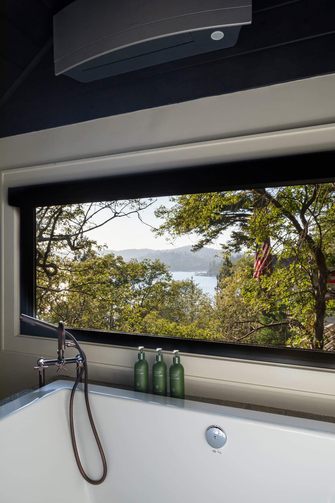 Soaking tub framed by a window looking out to the lake